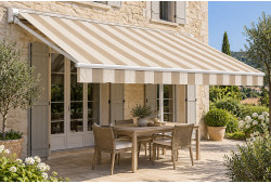 Toile de store banne à rayures beige et écru, déployée au-dessus d’une terrasse avec table et chaises.