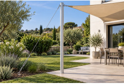 Hauban inox avec ridoir reliant un mât aluminium à un ancrage au sol, près d’une terrasse équipée d’une voile d’ombrage.